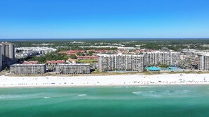 A coastal hotel complex with multiple buildings, a beach, and a clear blue sky. - Fairway to Shore - your peaceful, fun and cozy beach villa! (Panama City Beach)