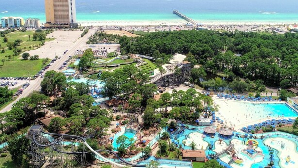 An aerial view of a resort with a large water park, a beach, and a pier. - Fairway to Shore - your peaceful, fun and cozy beach villa! (Panama City Beach)