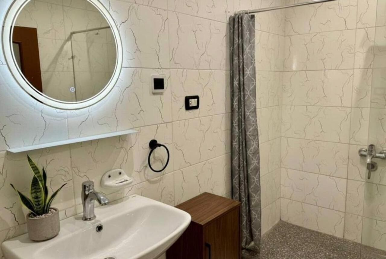 Une salle de bain équipée d’un lavabo, d’un miroir, d’un porte-serviettes et d’un rideau de douche.