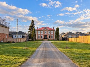 Une rue résidentielle bordée d’une maison en briques, d’une allée gravillonnée et d’une clôture en bois.