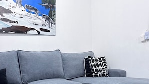 A modern living room with a grey sofa, a black coffee table, and a painting of wolves on a snowy landscape. - Greg black apartment - WITH AC/NETFLIX,HOTSHOWER (Mombasa)