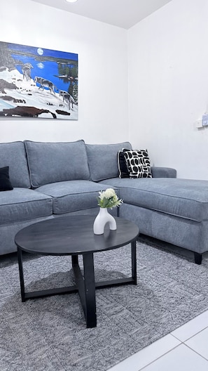 A modern living room with a grey sofa, a black coffee table, and a painting of wolves on a snowy landscape. - Greg black apartment - WITH AC/NETFLIX,HOTSHOWER (Mombasa)
