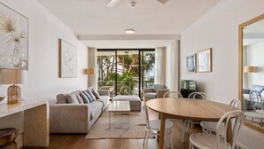 Un soggiorno moderno con divano, tavolino, tavolo da pranzo e sedie. Si nota una ventola a soffitto, una televisione e opere d'arte alle pareti.