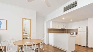 Una cucina moderna con mobili bianchi, un'isola in legno e un frigorifero bianco.