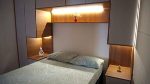 Ein Schlafzimmer mit einem Bett, Nachttischen und einem an der Wand befestigten Regal mit einer Vase.