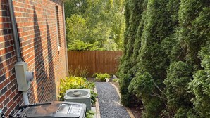 A narrow pathway leading to a brick building with a trash bin and outdoor electrical box. - Little Brick House - 10min from New River Gorge Bridge (Fayetteville)