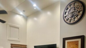 A living room with a flat-screen TV, a decorative wall clock, and a framed historical document. - Little Brick House - 10min from New River Gorge Bridge (Fayetteville)