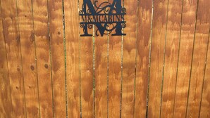 Una cerca de madera con un letrero de metal que dice 'M&MCABINS'.