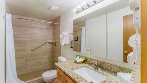 Une salle de bain avec douche, toilettes, un meuble-lavabo et un grand miroir.