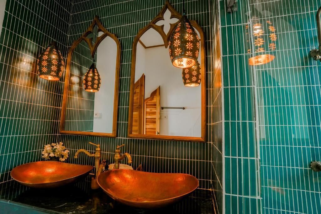 A bathroom with two copper sinks, a mirror, and decorative lanterns.