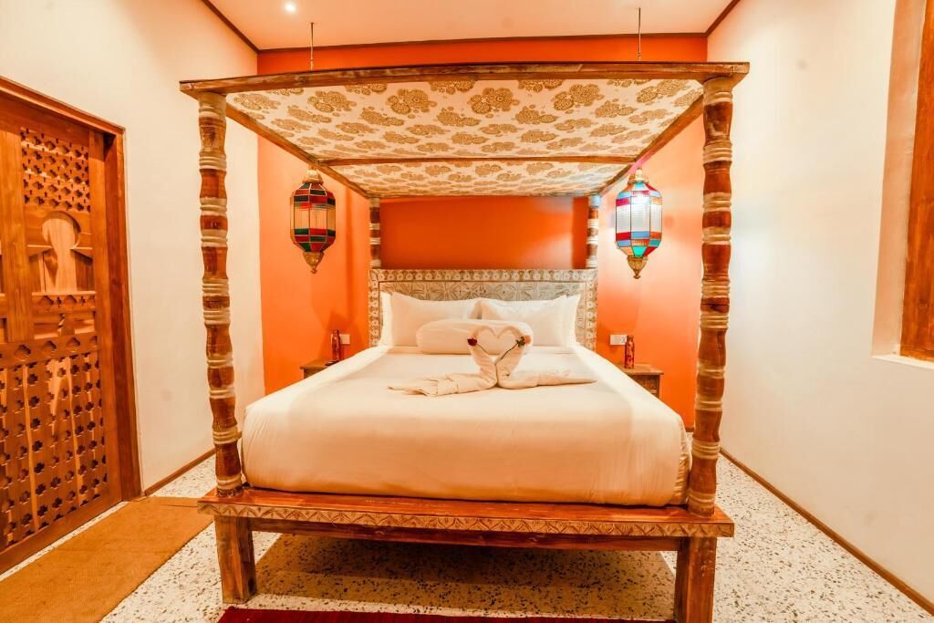 A four-poster bed with a canopy, a wooden door with a lattice design, and a wall-mounted lantern.