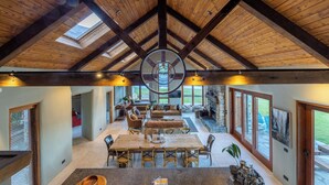 Un interior espacioso con un alto techo de madera, un tragaluz circular central y grandes ventanales con vistas al exterior.