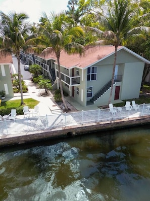 A modern building with a flat roof, a staircase, and a pool area with chairs. - Riverwalk Retreat | Waterfront Escape (Fort Myers)
