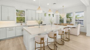 A modern kitchen with white cabinetry, a large island, and pendant lighting. - Salt House · 2026 Luxury · 6 King Suites 2 Masters (Fort Myers Beach)