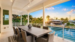 A dining area with a pool view, white railings, and a large window. - Salt House · 2026 Luxury · 6 King Suites 2 Masters (Fort Myers Beach)