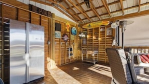 Een rustiek cabinteinterieur met houten inrichting, een koelkast, een eethoek met tafel en stoelen, en een bord waarop staat 'LANDSHARK'.