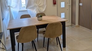 Un coin repas avec une table en bois, quatre chaises, une plante en pot et un extincteur fixé au mur.