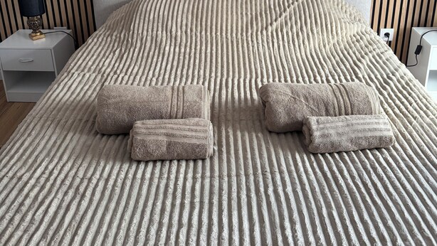 Un lit bien fait, avec une couvre-lit à rayures et deux serviettes pliées.