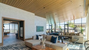 A spacious living area with a high ceiling, large windows, and a mix of seating arrangements including sofas and chairs. - Deluxe Stay 5mins to Convention Center (Phoenix)