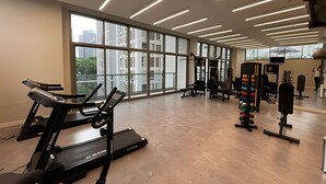 Ein Fitnessstudio mit Laufbändern, Kraftgeräten und einem großen Fenster.