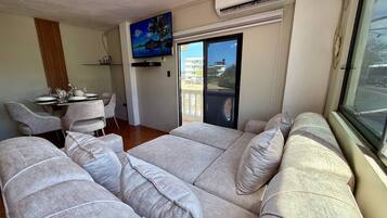 Appartamento Comfort, balcone, vista mare parziale | Area soggiorno | TV a schermo piatto 55 pollici con canali digitali, Netflix