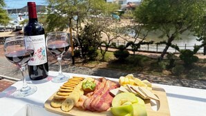 A table with a bottle of wine, two glasses, and a variety of snacks. - ALMAR (Puerto Baquerizo Moreno)