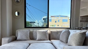 A sectional sofa with a view of buildings through a window. - ALMAR (Puerto Baquerizo Moreno)