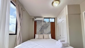 A bedroom with a bed, a window with curtains, an air conditioning unit, a television, and a wardrobe. - ALMAR (Puerto Baquerizo Moreno)