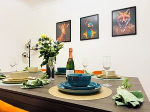 Ein Esstisch, gedeckt mit Tellern, Schüsseln, Gläsern und einer Champagnerflasche.