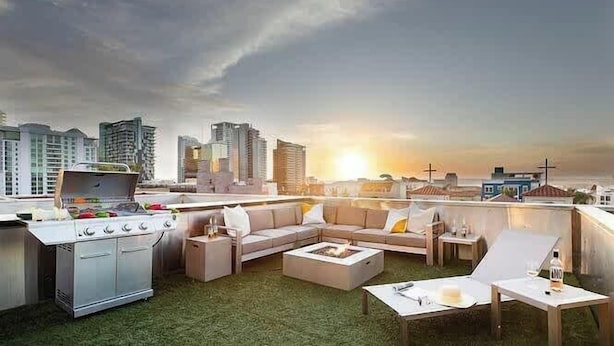 Terraza en la azotea con parrilla, zona de estar y vistas al horizonte de la ciudad.