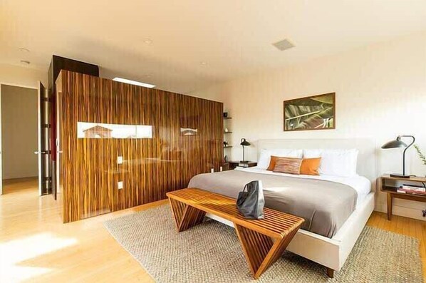 Une chambre moderne comprenant un lit, des tables de chevet, un banc et une cloison en bois.