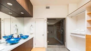 Un baño moderno con ducha, un lavamanos de color azul y un espejo.