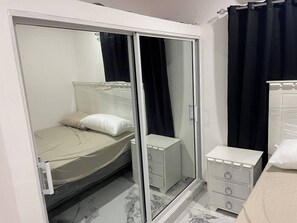 Une chambre à coucher comprenant un lit, une armoire, une table de chevet et un miroir.