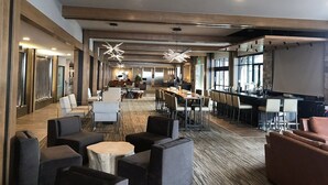 Eine moderne Hotelhalle mit einer langen Rezeption, mehreren Sitzbereichen und einem großen Bildschirm für Präsentationen.