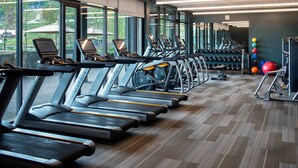 Ein Fitnessstudio mit Laufbändern, Kraftgeräten und Kurzhanteln.