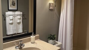 Een badkamer met een wastafel, spiegel, handdoekhouder, toilet en douchegordijn.