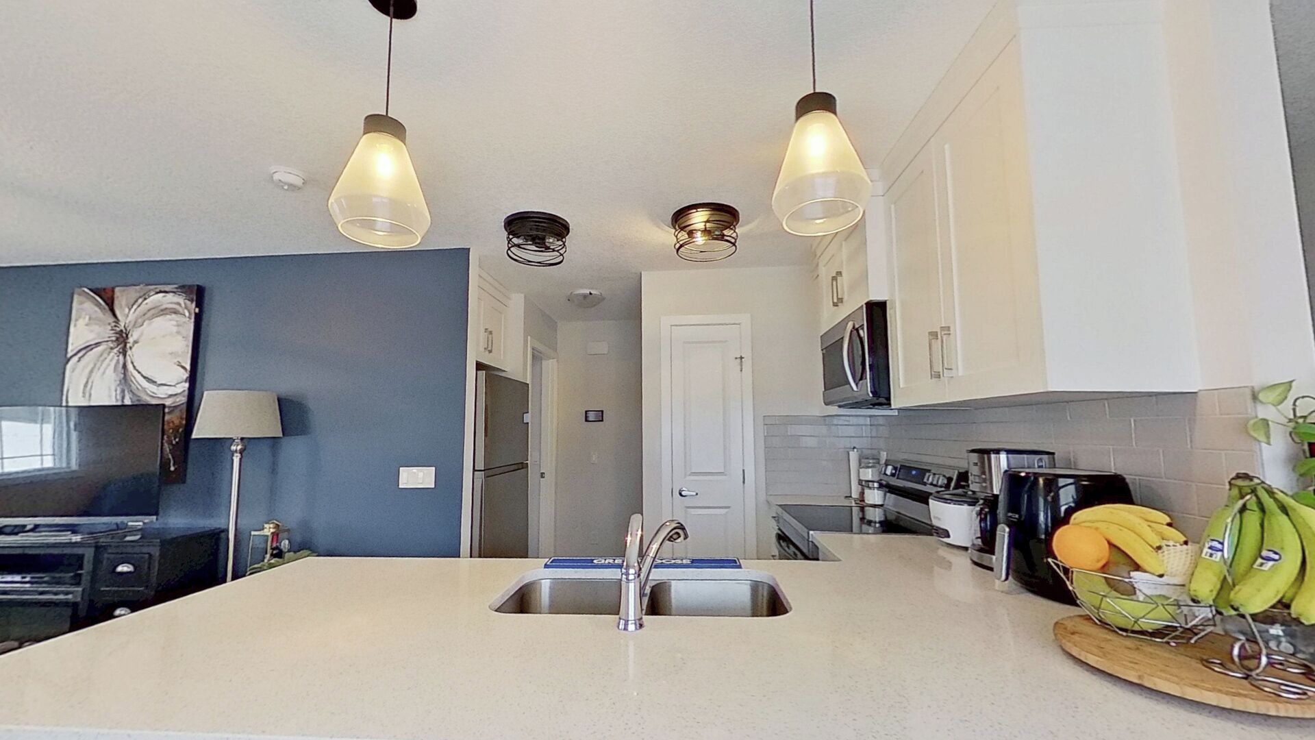 Een moderne keuken met een centraal eiland, roestvrijstalen apparatuur en hanglampen.
