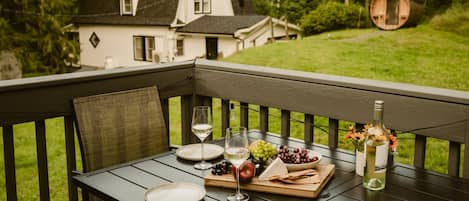 A wooden deck with a table set for a meal, featuring plates, glasses, and a variety of food items.