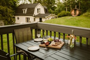 Eine Holzterrasse mit einem Esstisch, gedeckt mit Tellern, Gläsern und verschiedenen Speisen.