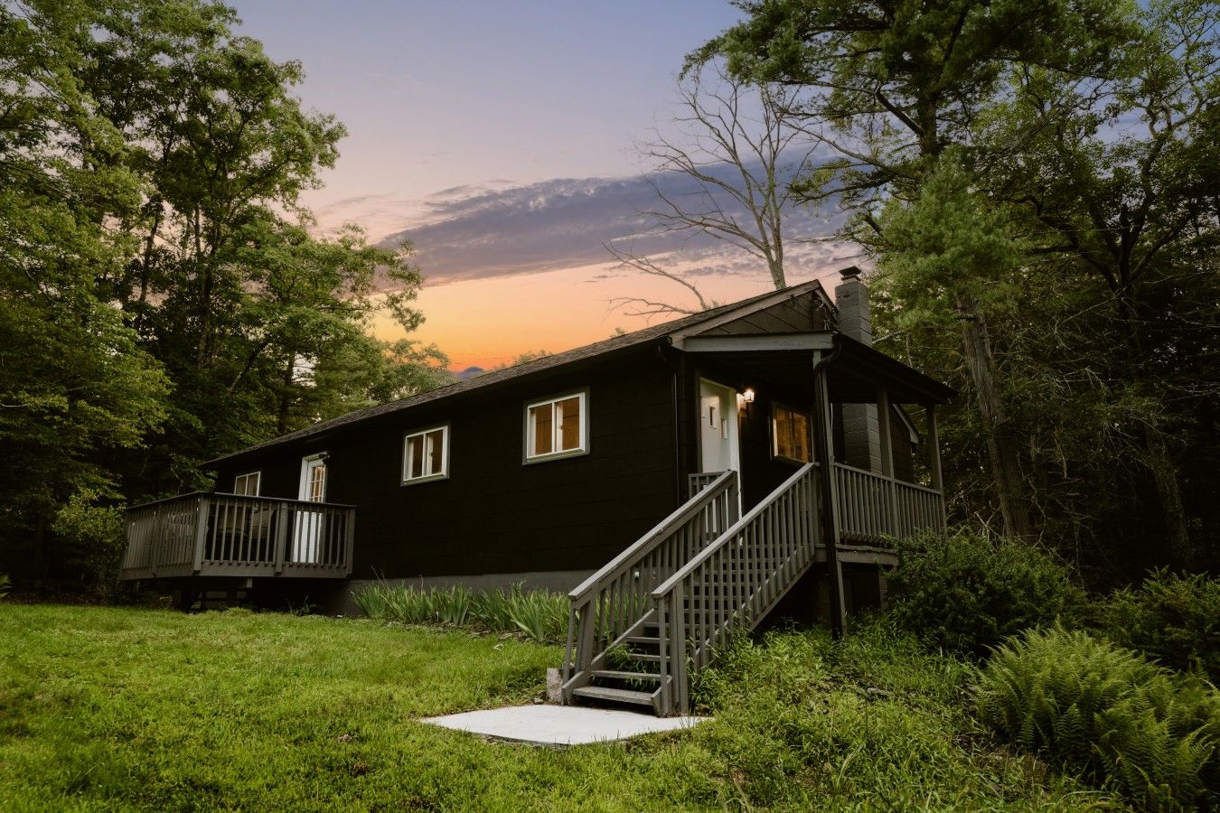 Une cabane à deux étages dotée d’une terrasse en bois et d’un escalier menant à l’entrée.