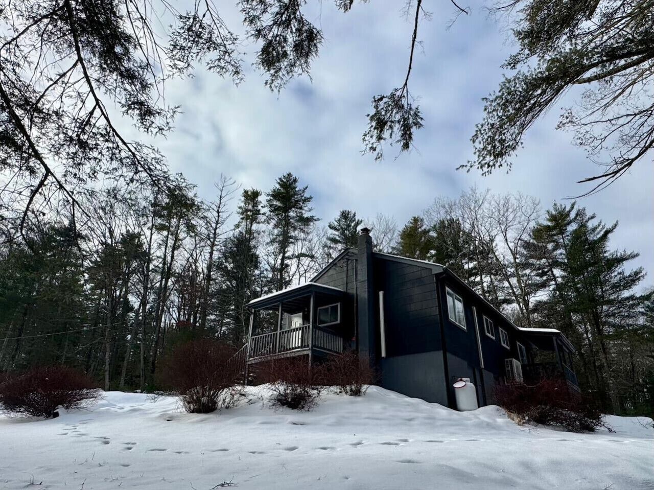 Une cabane à deux étages dotée d’un balcon, entourée d’une forêt et d’un paysage enneigé.