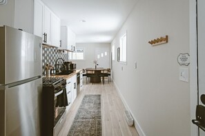 Eine moderne Küche mit weißen Schränken, einem Edelstahl-Kühlschrank und einem Essbereich mit Tisch und Stühlen.