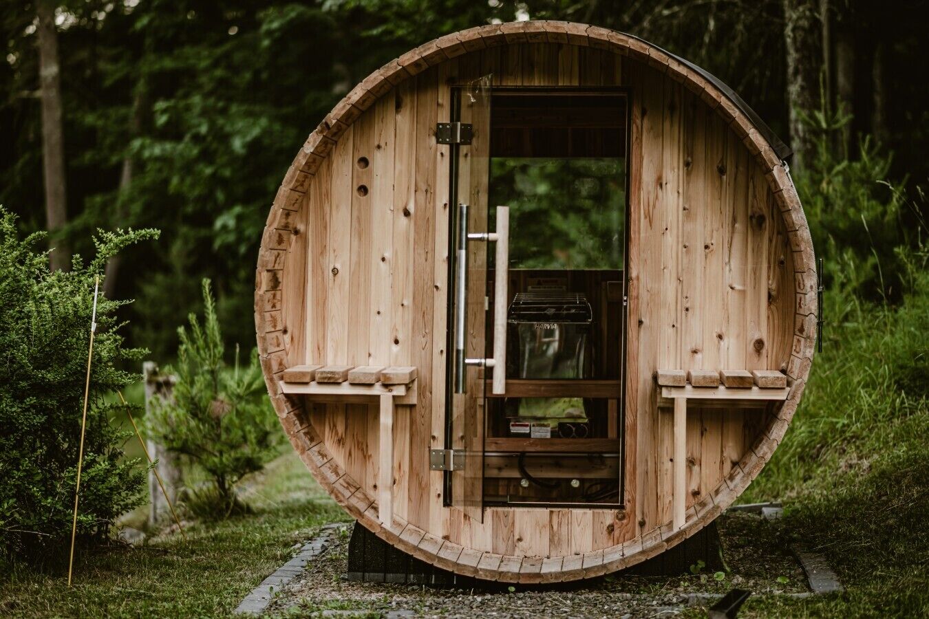 Una estructura de madera con forma de barril, con una puerta, un pequeño estante y una ventana.