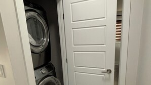 Un lavadero con lavadora y secadora, una puerta blanca y suelo de madera.