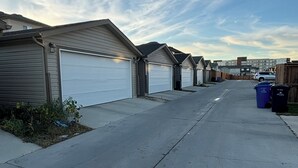 Una calle residencial con casas de un solo piso, puertas de garaje y cielo despejado.