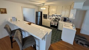 Eine moderne Küche mit Kochinsel, Kühlschrank, Backofen und Mikrowelle.
