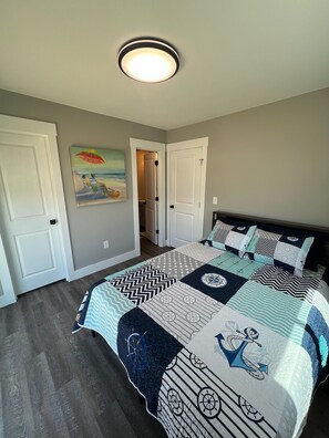A bedroom with a bed, a painting, and a door. - Oceanfront 3-bedroom townhome with AC & outdoor shower in North Topsail Beach (North Topsail Beach)
