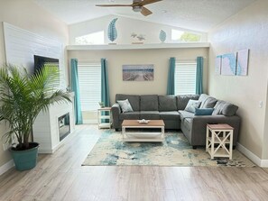 A living room with a sectional sofa, a coffee table, a potted plant, and a painting on the wall. - 3-bedroom house with Private Pool, Sauna & Game Room Oasis (Spring Hill)