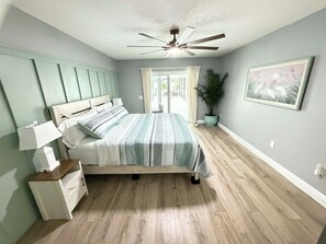 A bedroom with a bed, bedside table, nightstand, ceiling fan, potted plant, and a framed picture on the wall. - 3-bedroom house with Private Pool, Sauna & Game Room Oasis (Spring Hill)