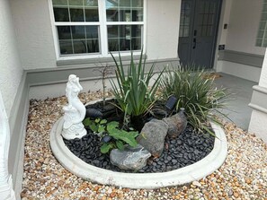 A garden bed with a white statue, various plants, and rocks. - 3-bedroom house with Private Pool, Sauna & Game Room Oasis (Spring Hill)